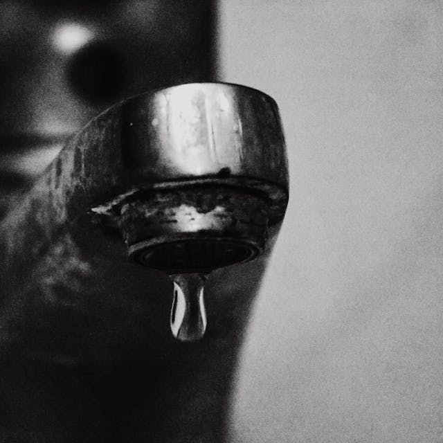 Faucet with Dripping Water in Grayscale Photography